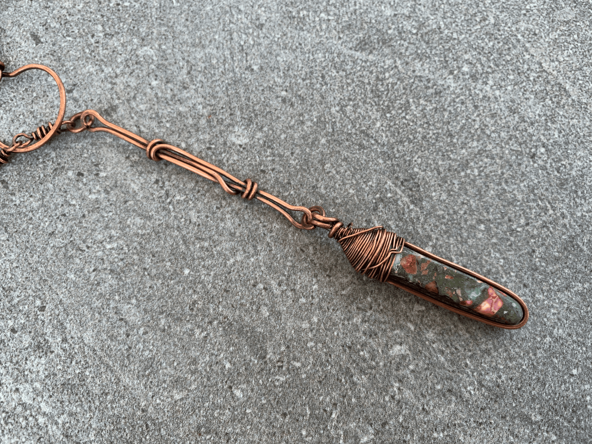 detail of lariat pendant showing wire wrapping on top and blue and red details of jasper stone